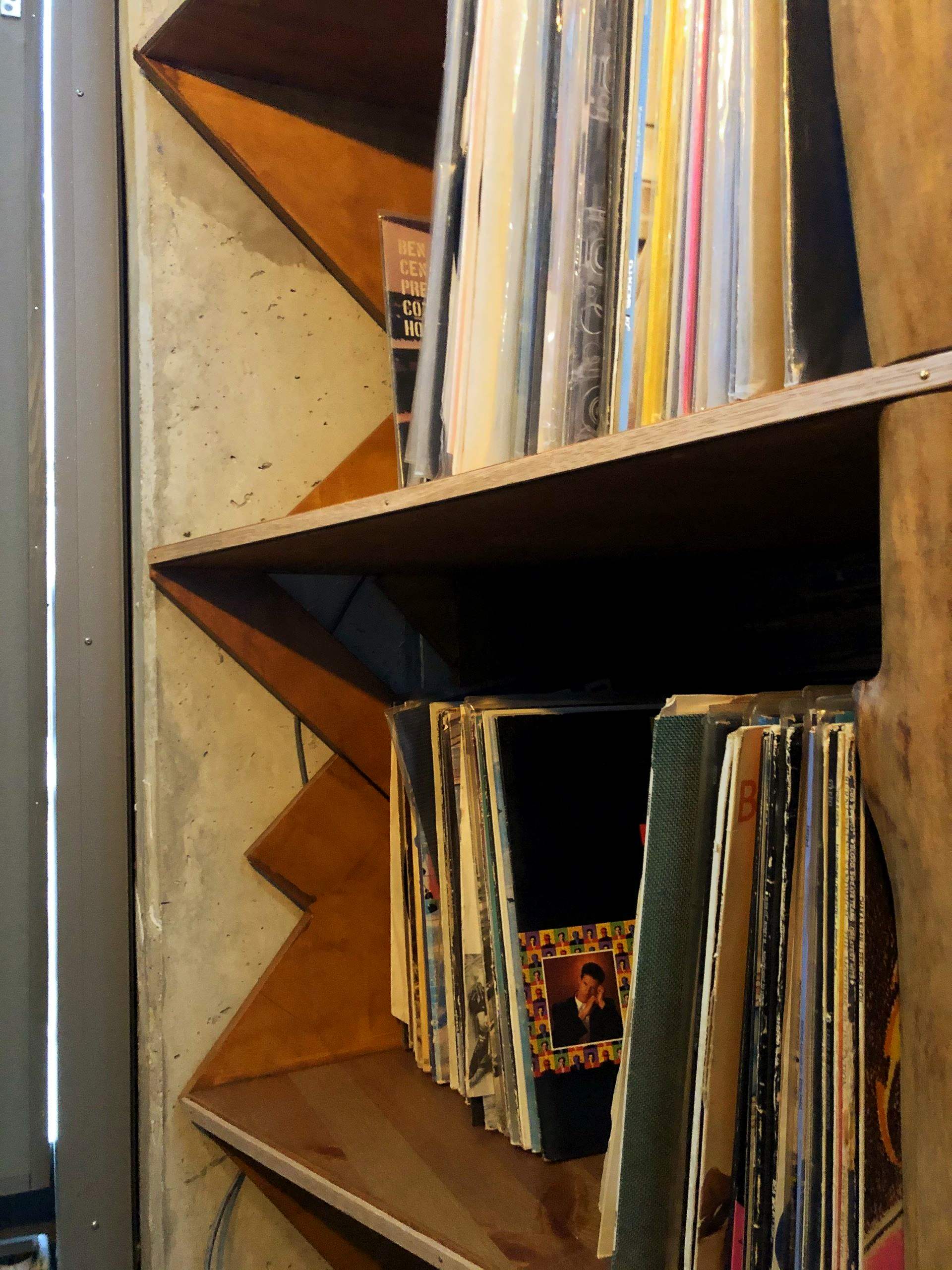 Platenalbums staan ​​op een houten plank met een zigzagpatroon. De albums hebben verschillende kleuren.