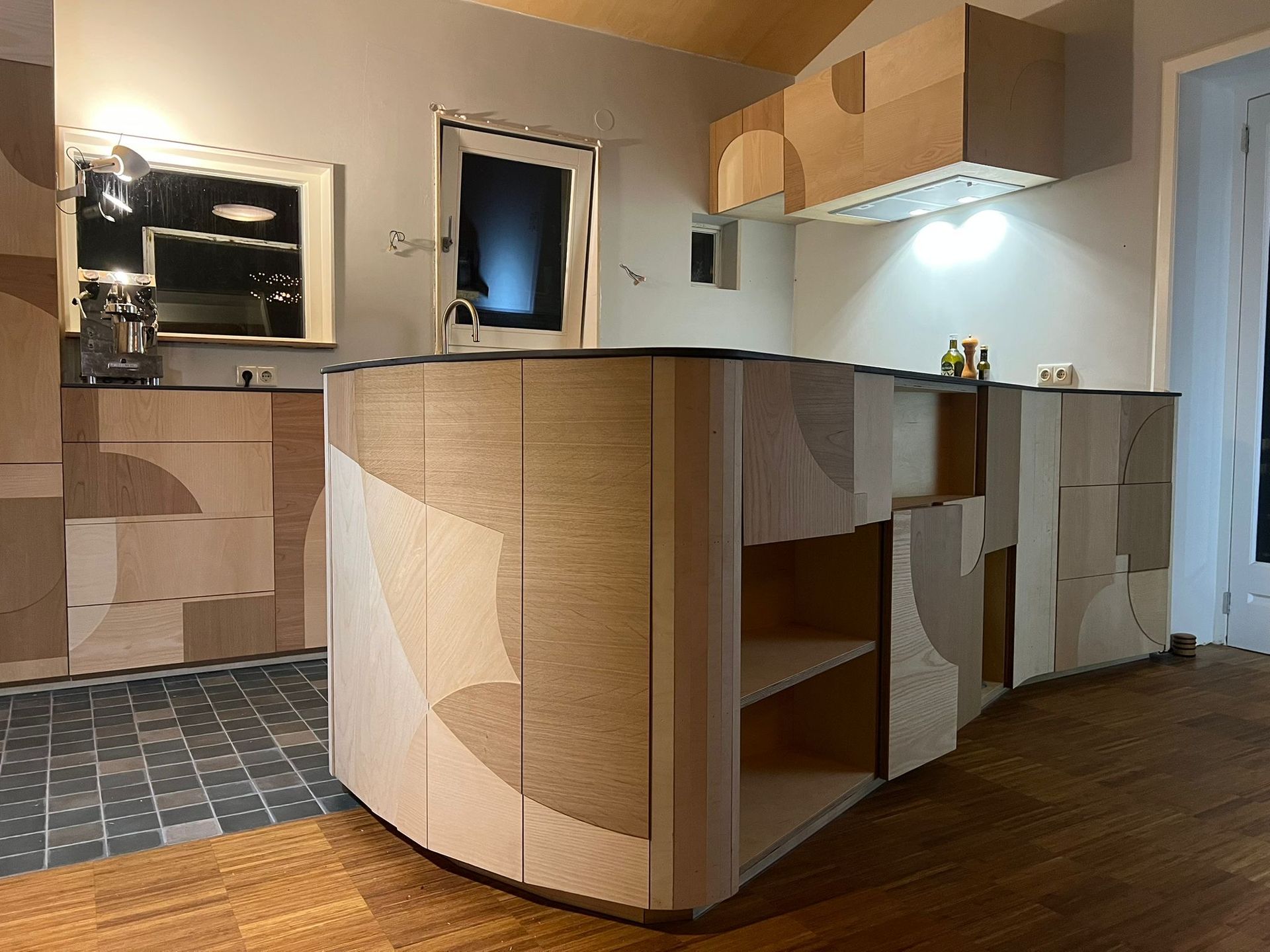 Moderne keuken met gebogen kookeiland en op maat gemaakte houten lambrisering in beige en crèmekleuren.
