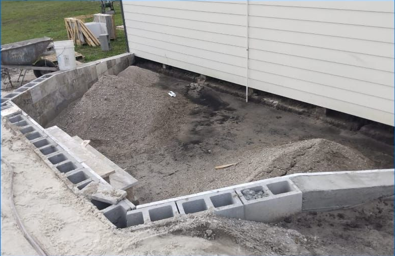 Construction site: concrete blocks forming a foundation for a building with a gravel-filled interior.