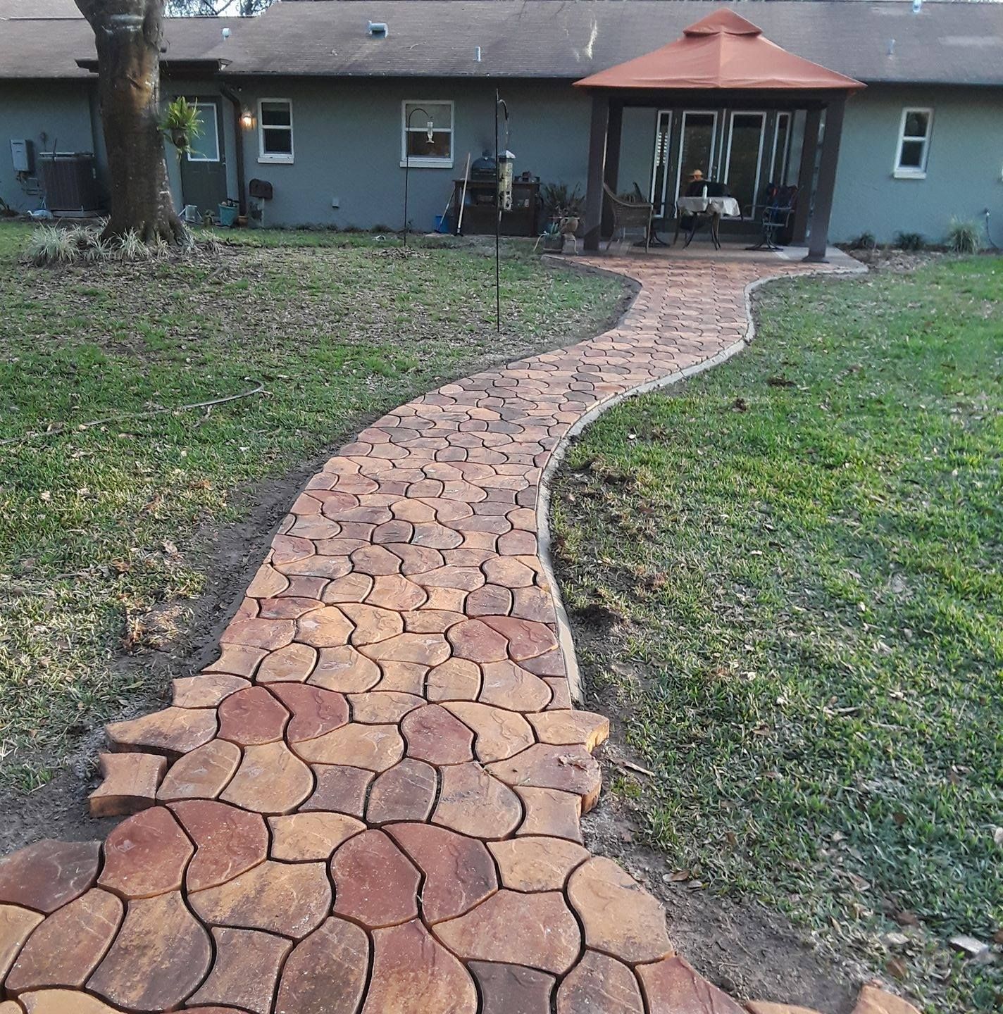 A winding stone path leads to a gazebo in a grassy backyard.