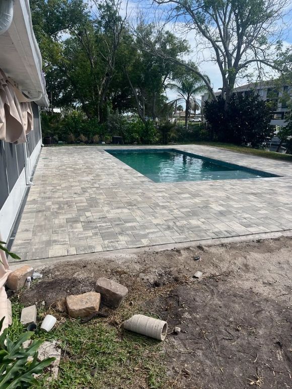 Brick driveway in mottled earth tones leads to a white stucco house with arched windows and bicycles parked in front.