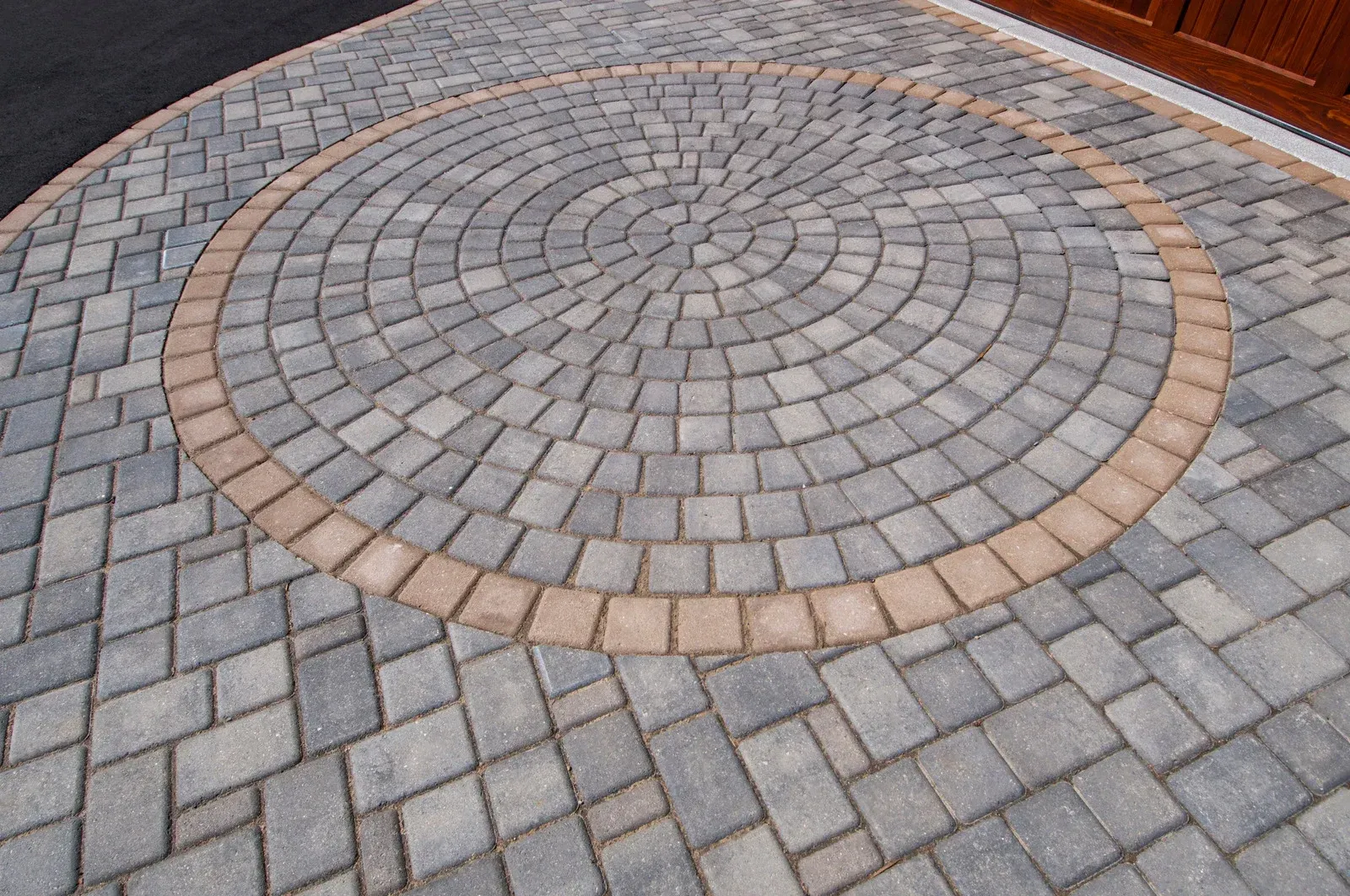 Circular brick driveway with a patterned center circle and a tan border.