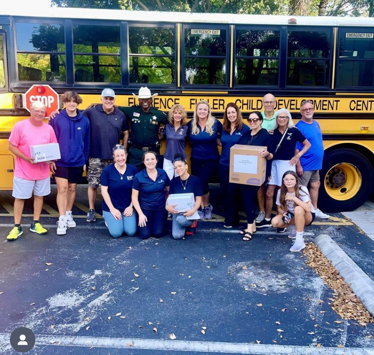 A group of people posing in front of a yellow bus that says fisher child development center