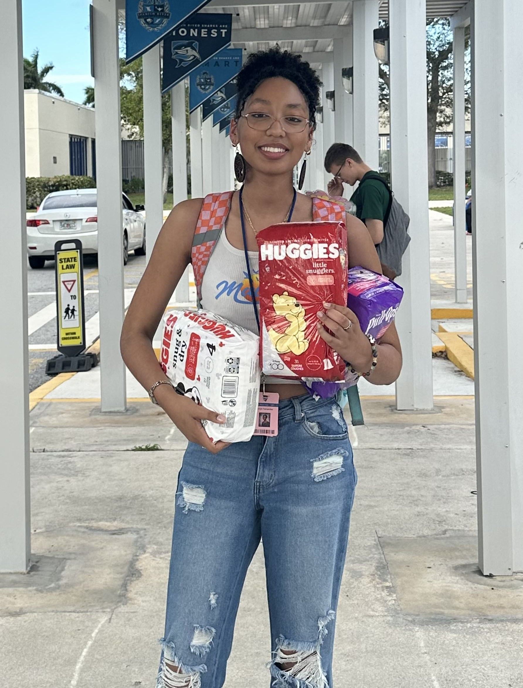 A woman is holding a bag of huggies diapers.