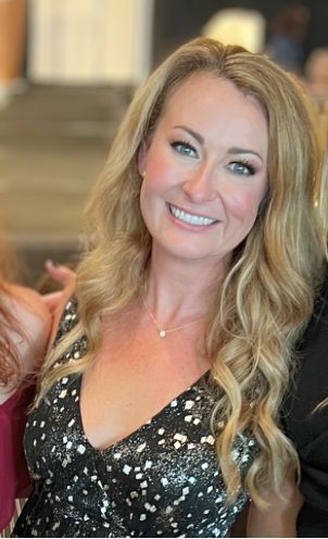 A woman in a black dress is smiling for the camera.