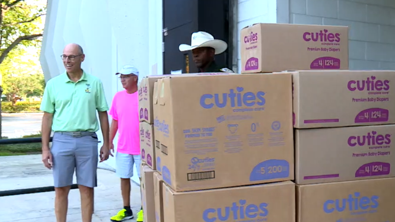 Two men are standing next to a stack of cuties boxes