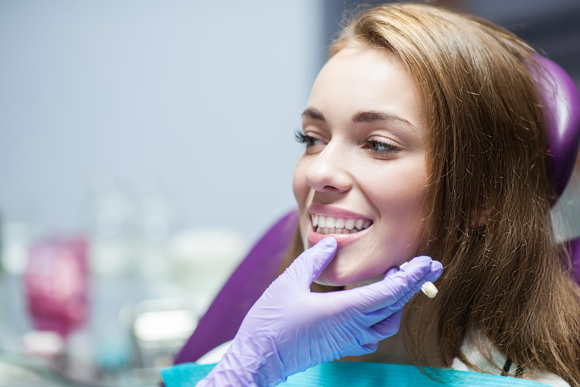 Smiling patient with purple gloves at a dental clinic, receiving a teeth checkup