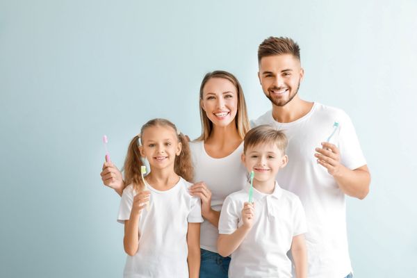 Family smiling with toothbrushes, promoting healthy dental care together. Family smiling with toothbrushes, promoting healthy dental care together.