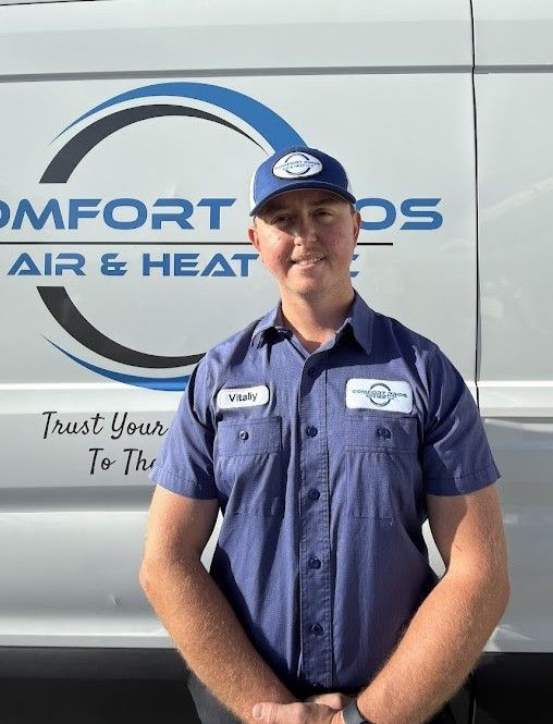 Uniformed HVAC worker standing in front of a Comfort Pros Air & Heat service van
