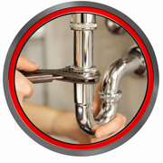 Plumber tightening a sink drain pipe with a wrench under a bathroom sink, red-circled close-up