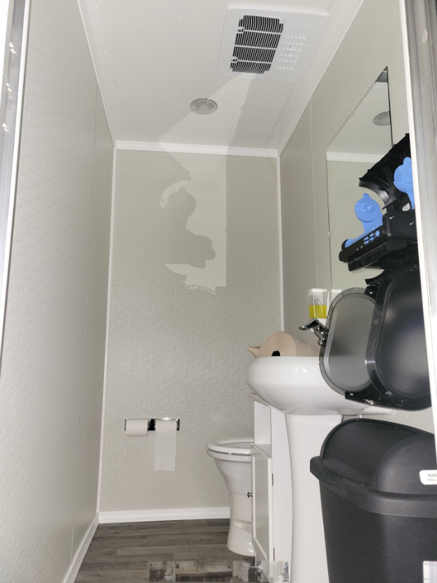 A bathroom with a sink , toilet and trash can