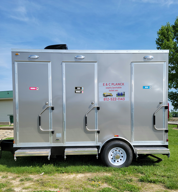 A silver trailer is parked in a grassy field.