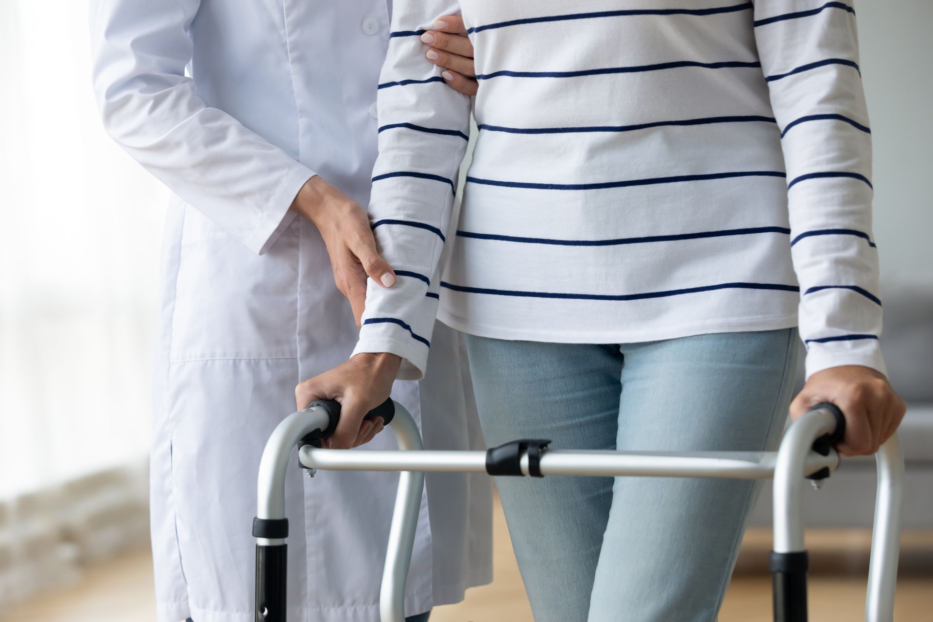 Person using a walker with a caregiver standing beside them indoors