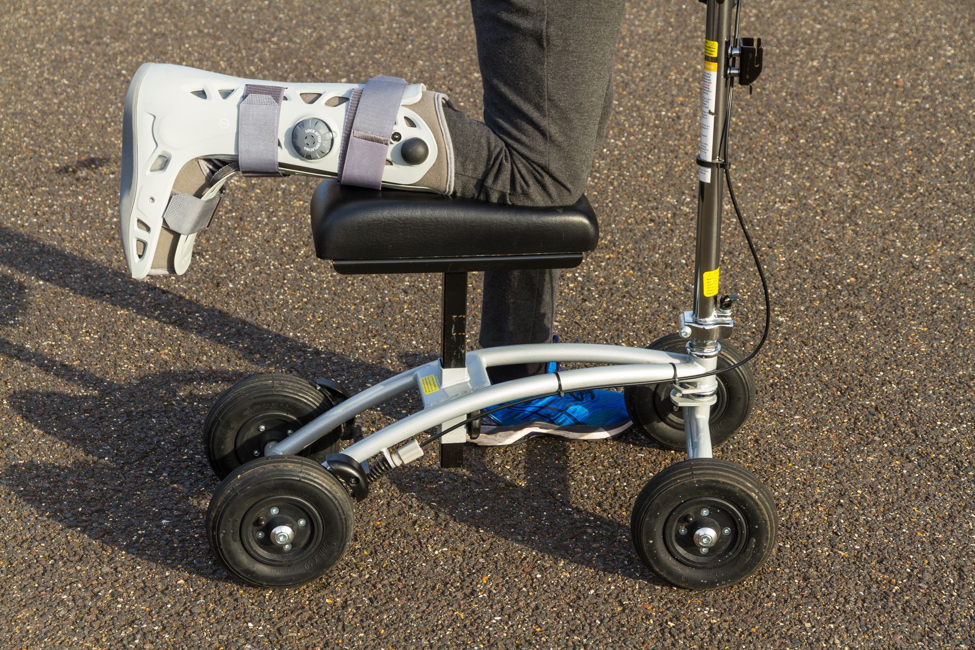 Foldable mobility scooter with black seat and silver frame on pavement outdoors