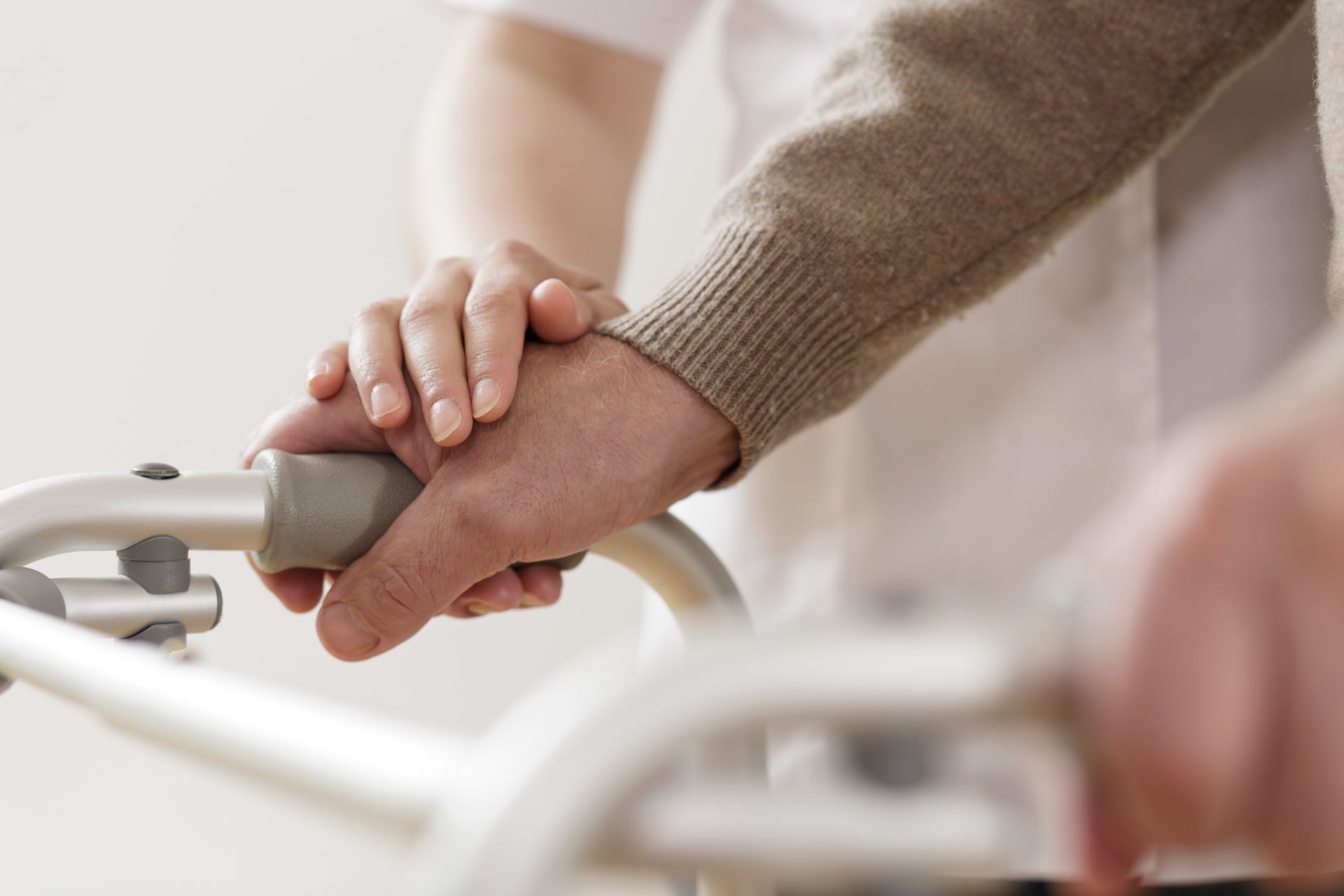 Hands gently holding a walker handle in a soft-lit indoor setting
