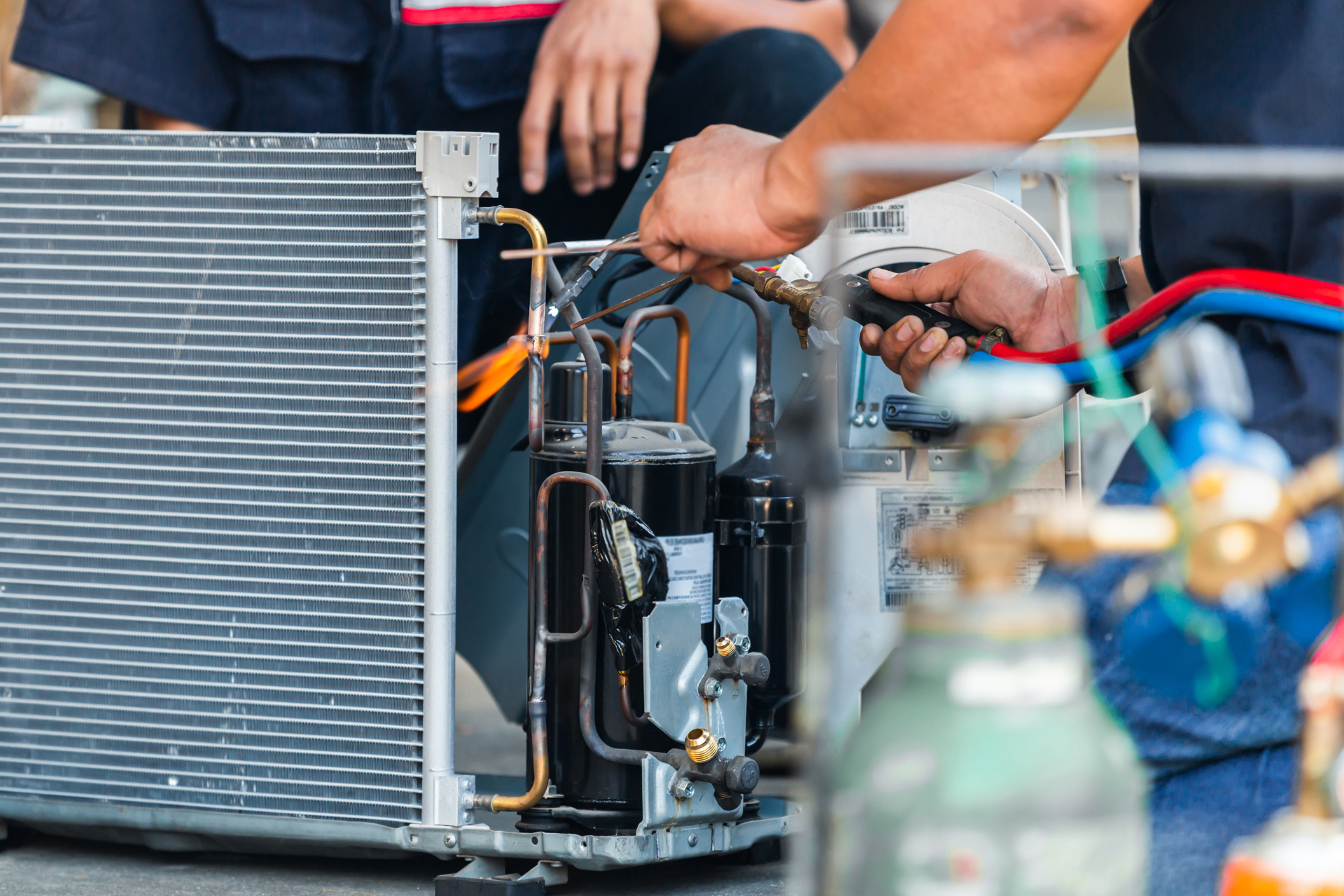 A man is working on an air conditioner with a screwdriver.