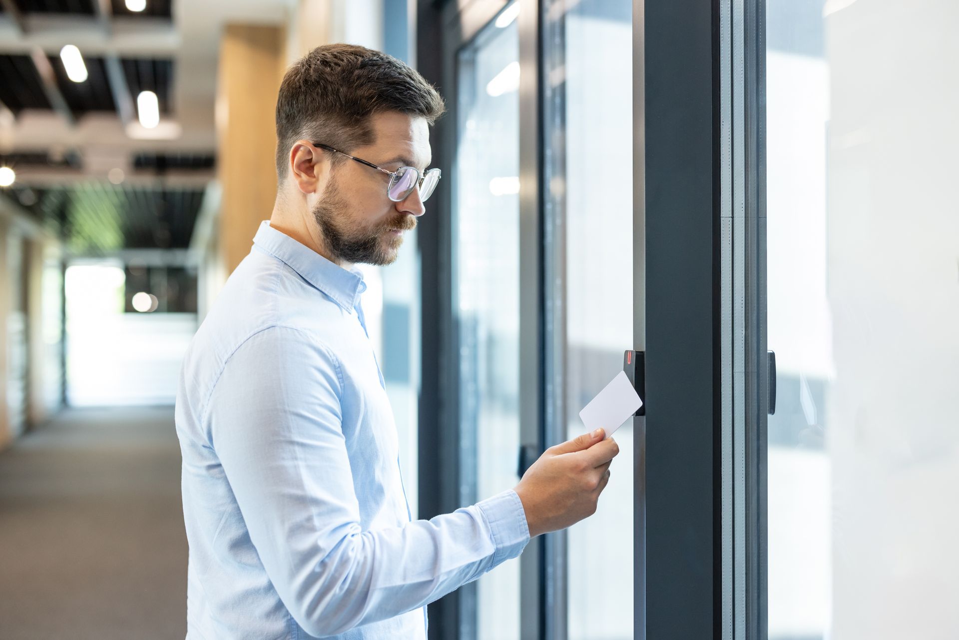 A man scans a key card at a glass office door for secure, contactless access.