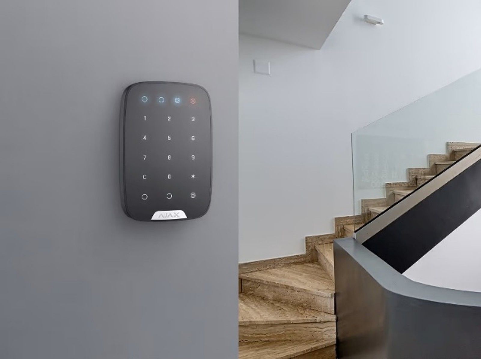 Photograph of a modern black keypad security system mounted on a gray wall.]