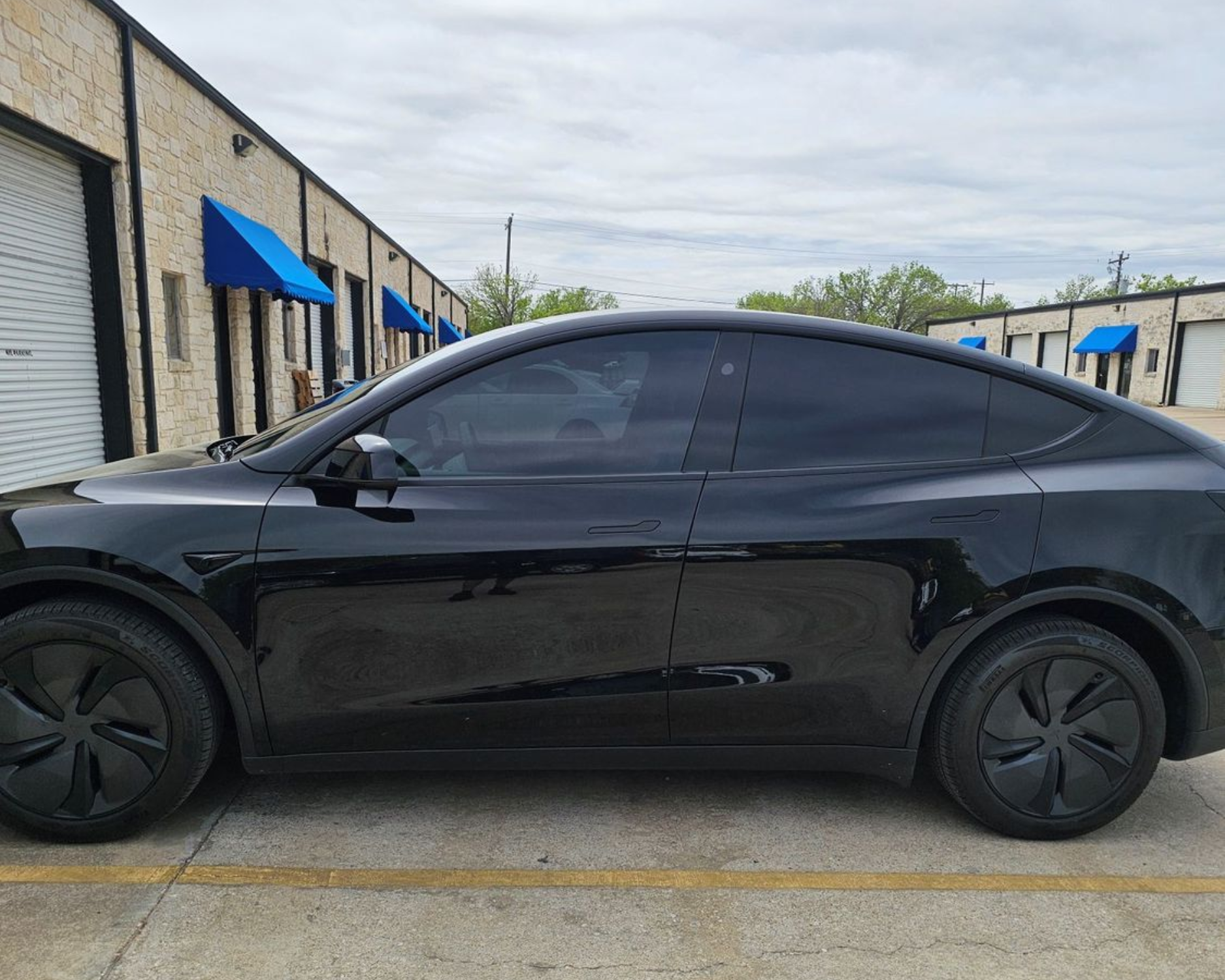 Black coupe parked beside a building with blue awnings