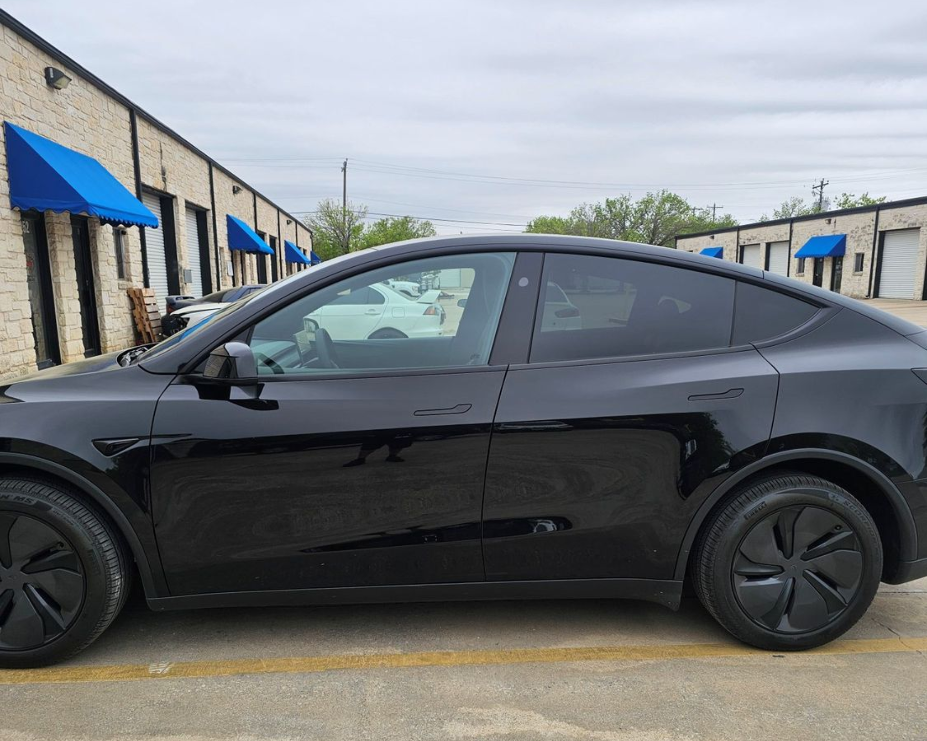 Black coupe parked in an alley beside storage units with blue awnings