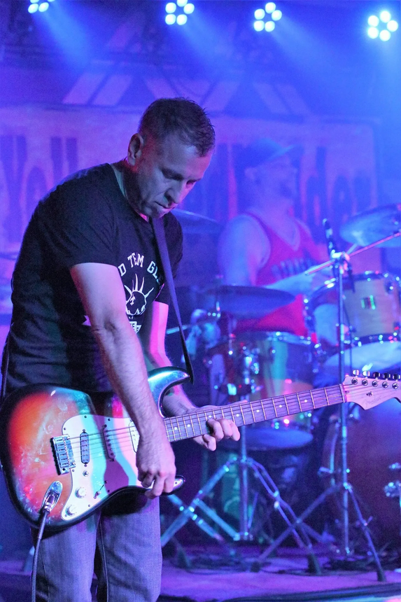 A man in a black shirt is playing a guitar on stage