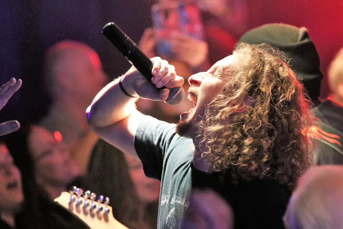 A man singing into a microphone in front of a crowd