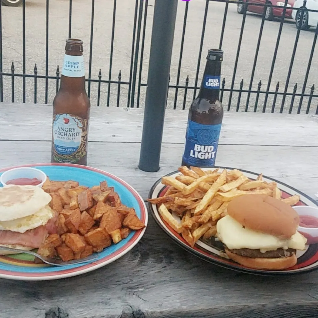 A bottle of bud light sits next to two plates of food