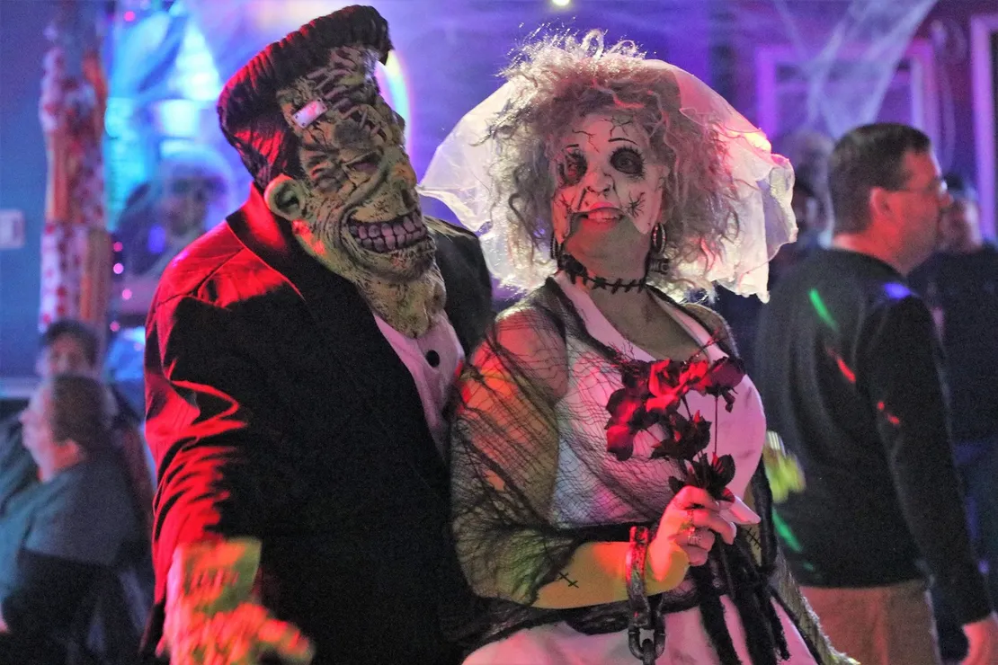 A man in a frankenstein costume stands next to a woman in a zombie costume