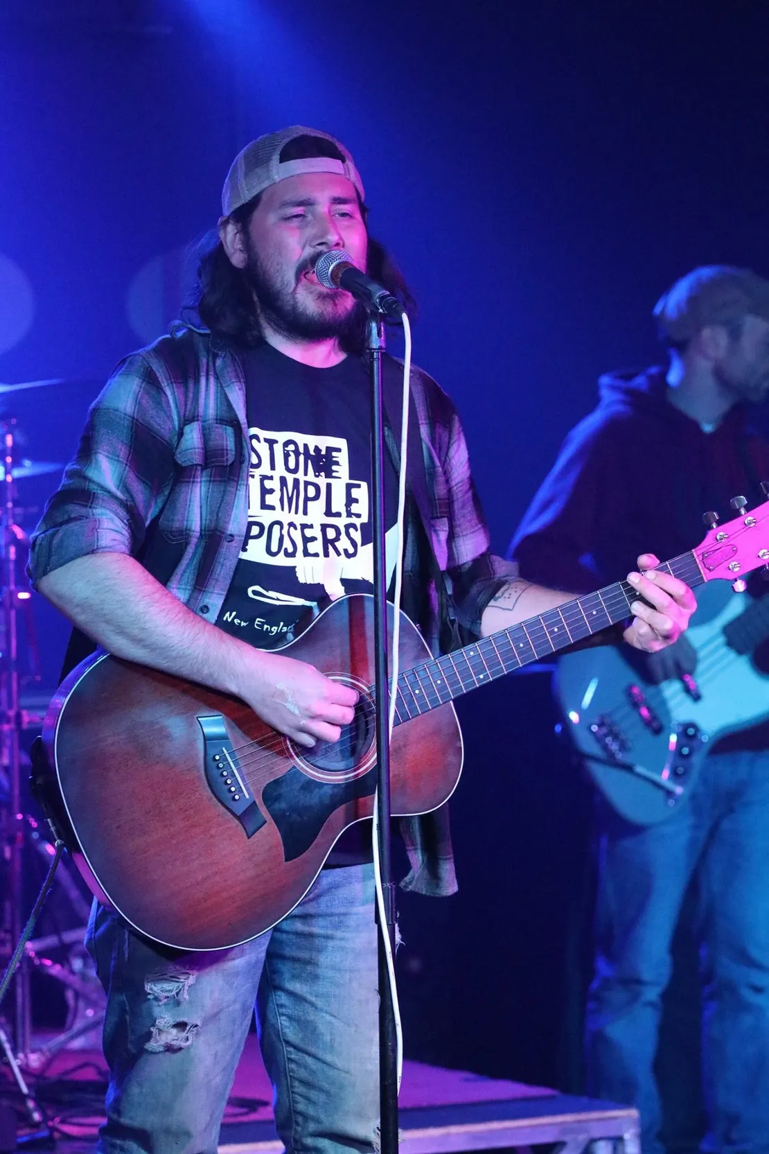 A man is playing a guitar and singing into a microphone on a stage.