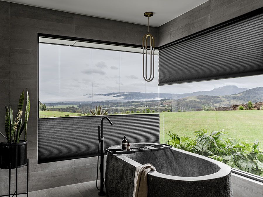 Luxurious bathroom with bathtub, window, and scenic mountain view.