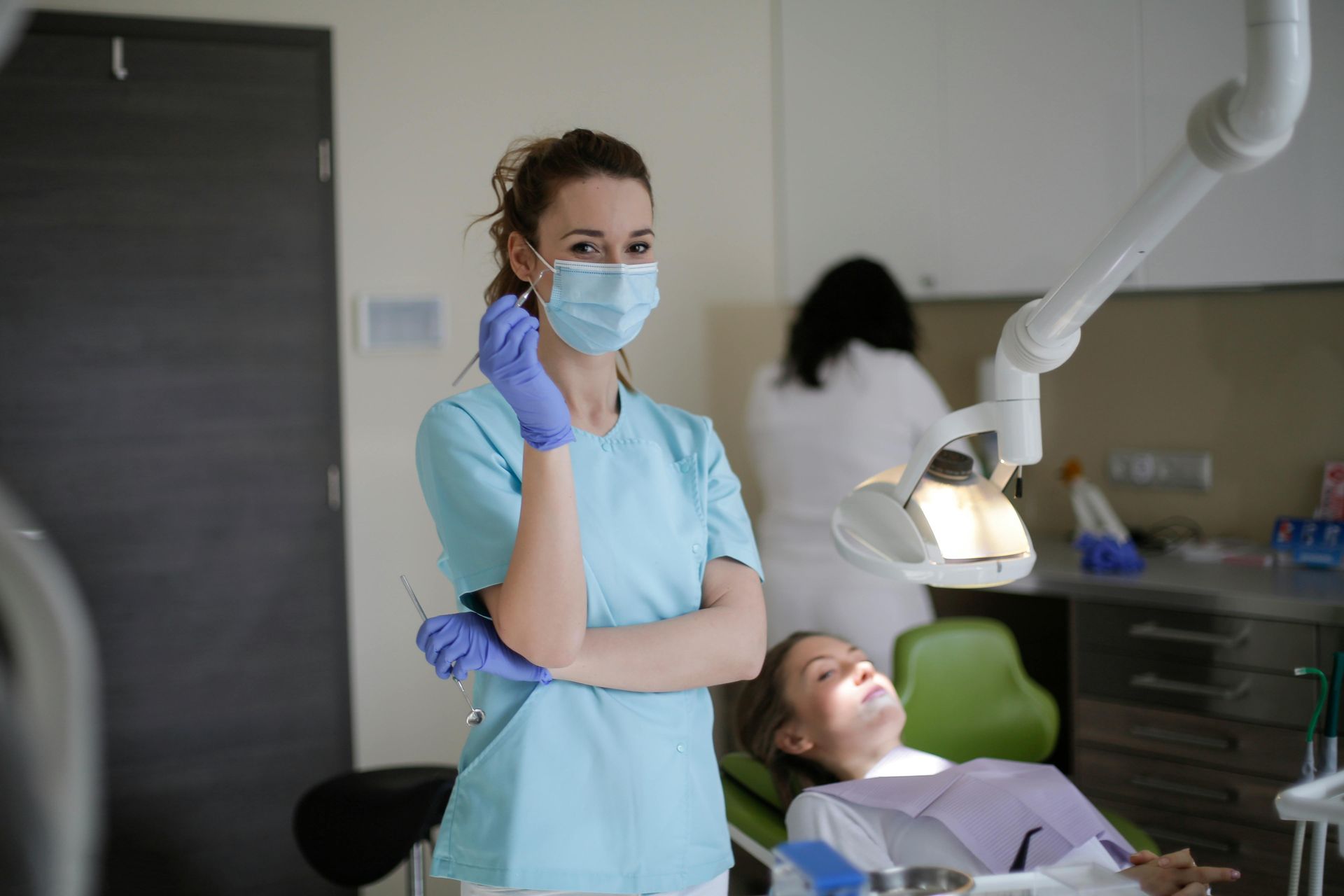 Dental assistant standing beside a patient in a dental chair during an exam