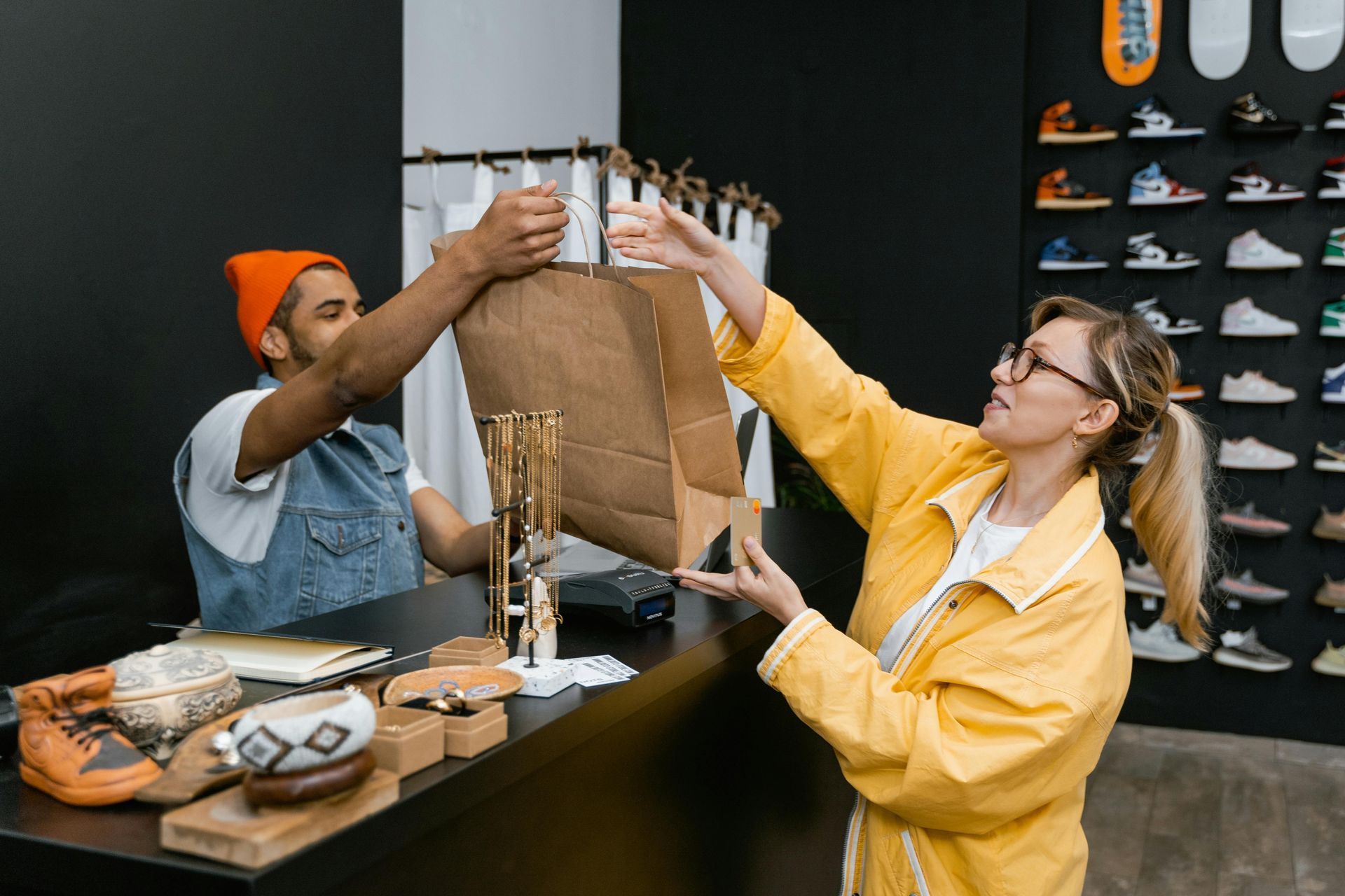 Two people inspecting a brown garment on a rack in a clothing store