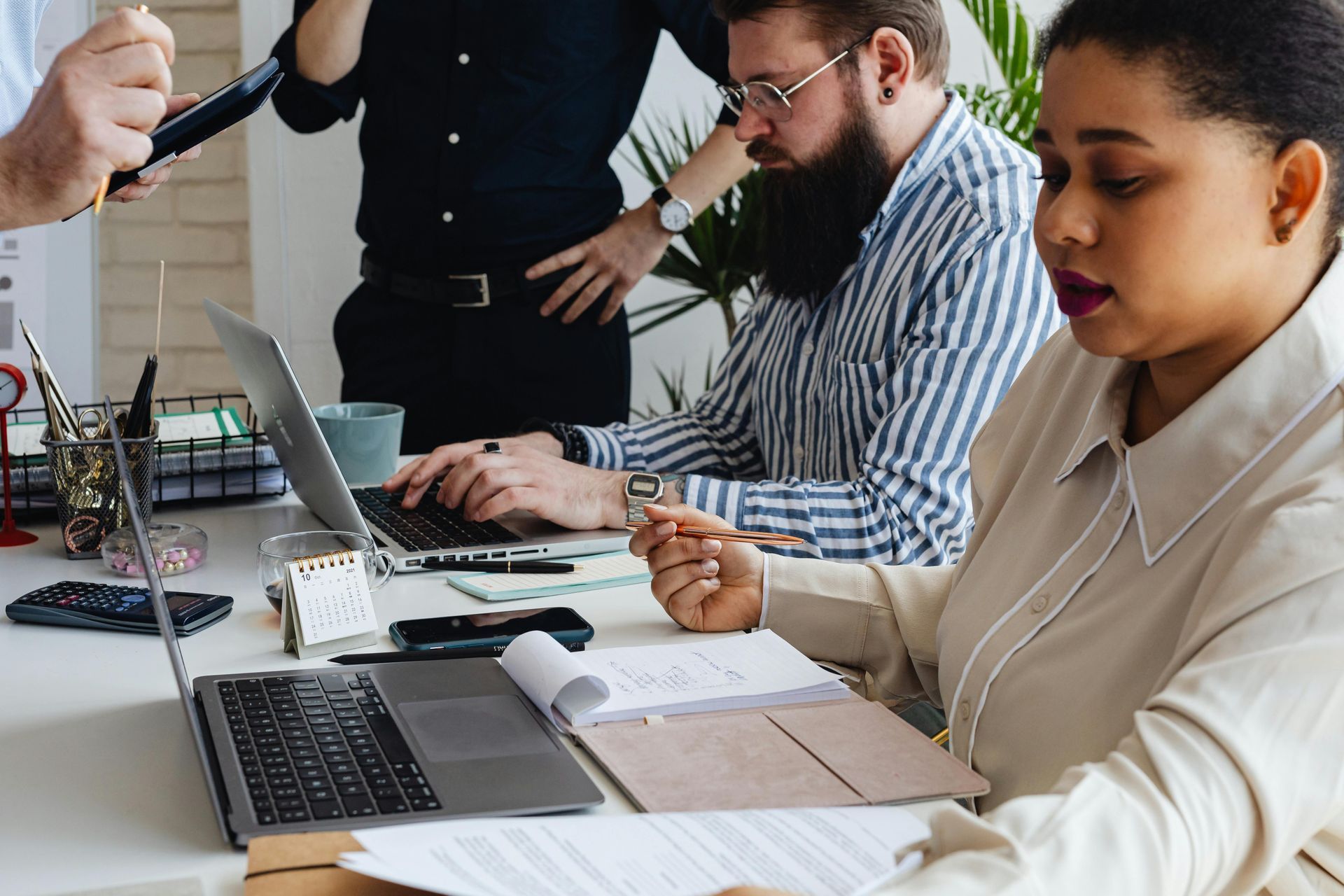People collaborating at a desk with laptops and notes in an office setting