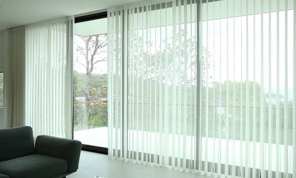 A Living Room With a Couch and Sliding Glass Doors With Vertical Blind — Curtain Force NQ in Garbutt, QLD