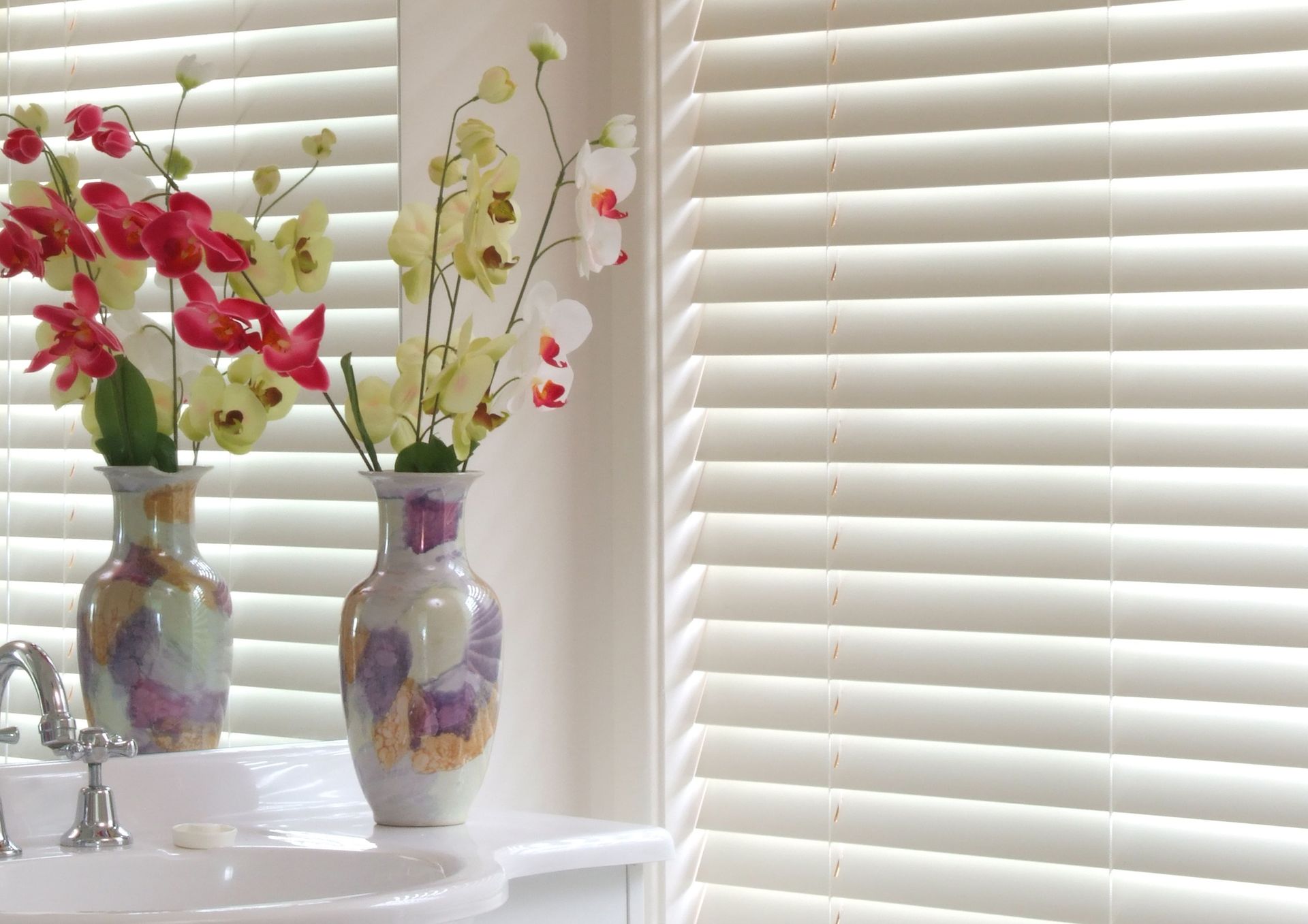 A Bathroom With Two Vases of Flowers in Front of a Window With Blind — Curtain Force NQ in Garbutt, QLD