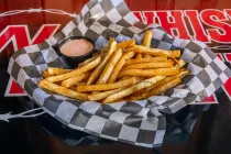 Basket of seasoned French fries in black-and-white checkered paper on a table