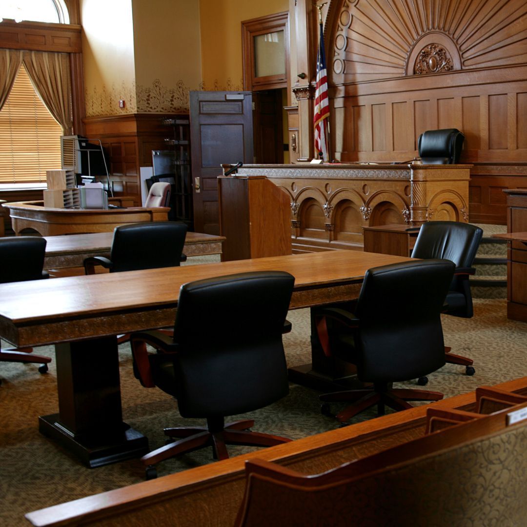 A courtroom with tables and chairs and an american flag