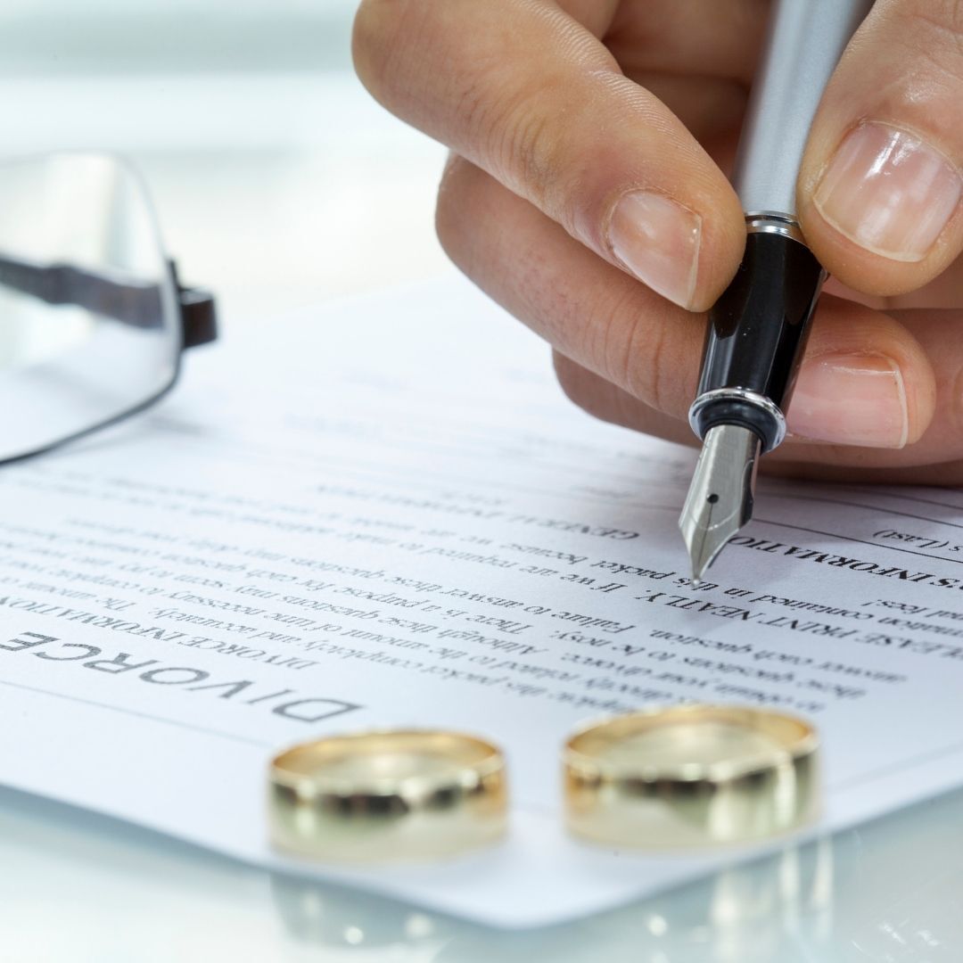 A person is writing on a piece of paper that says divorce