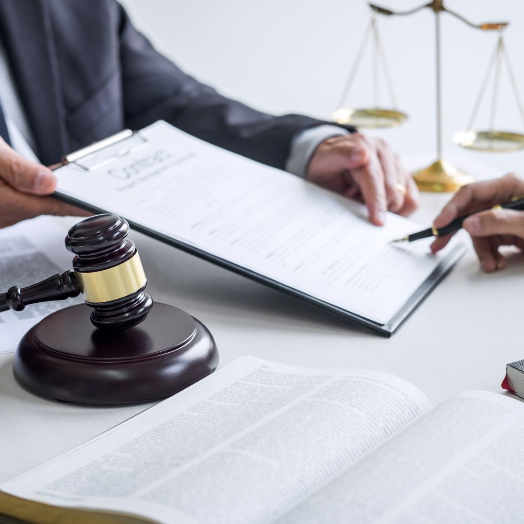 A man in a suit is holding a clipboard and a gavel.