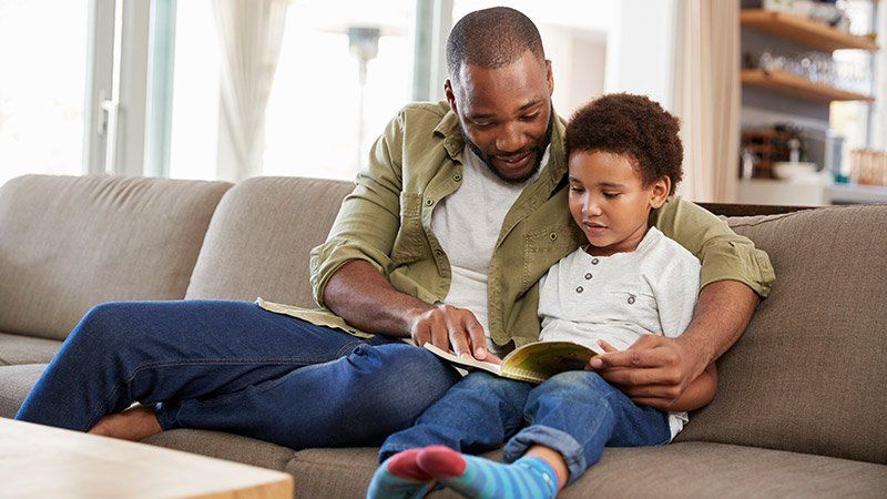 man reads young child a book