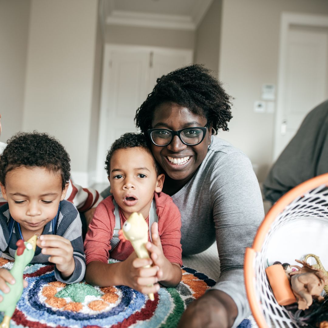 A woman is laying on the floor with two children.