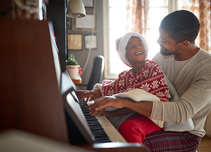 A man is teaching a little girl how to play the piano.
