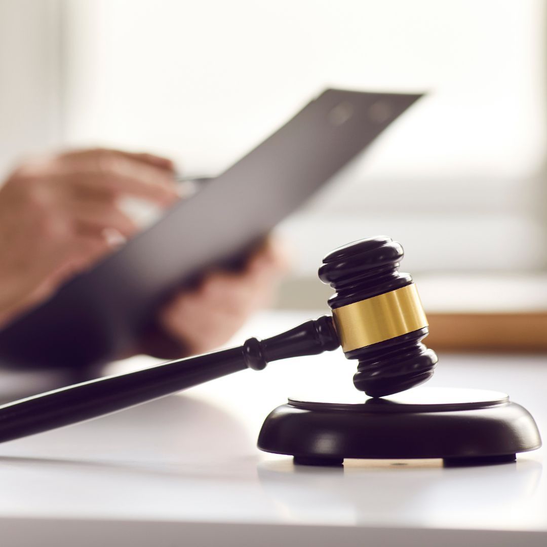 A judge 's gavel is on a table next to a person holding a clipboard