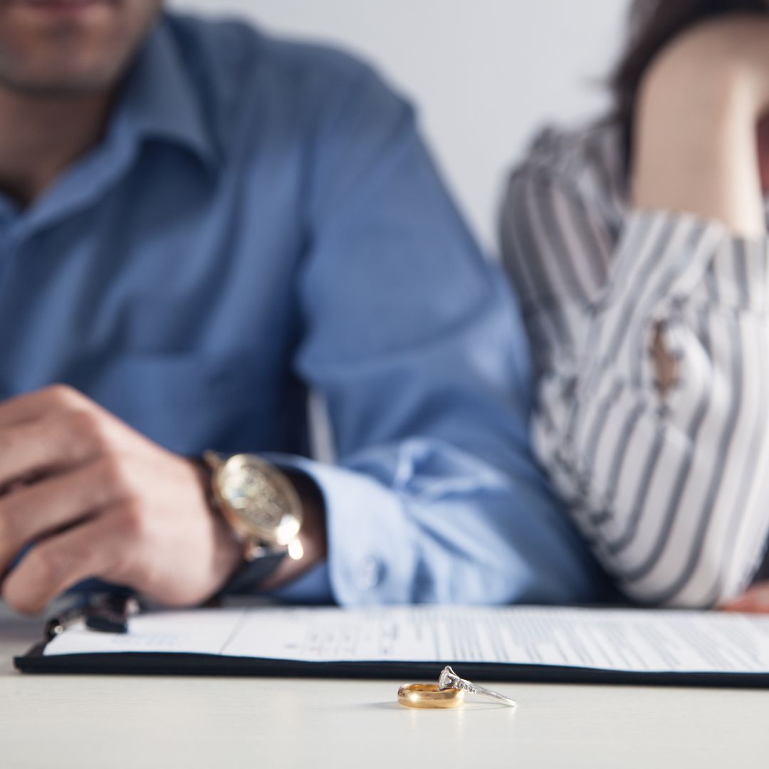 A man and a woman are sitting at a table with a ring on the table.