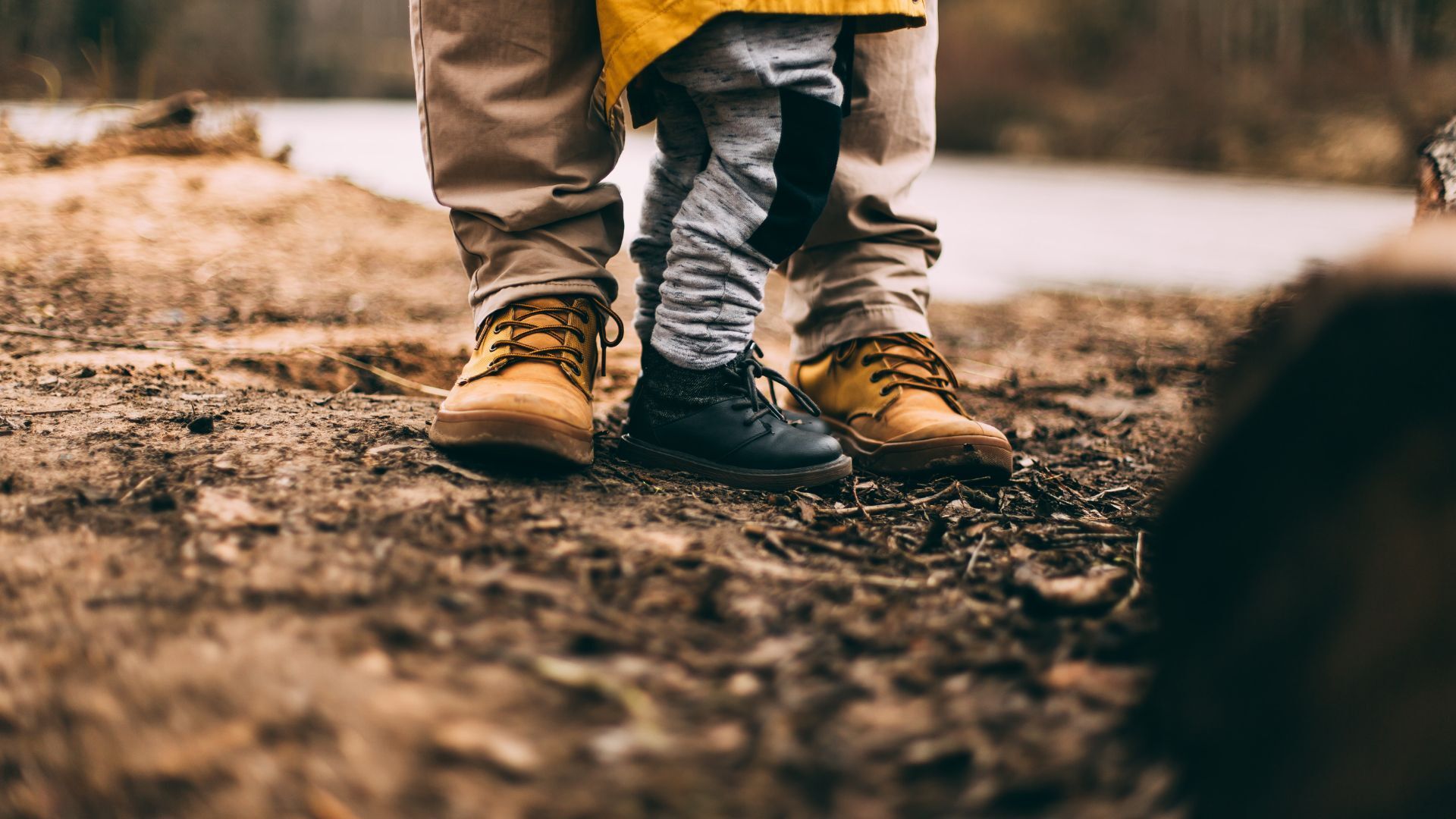 A man and a child are standing next to each other on a dirt road.
