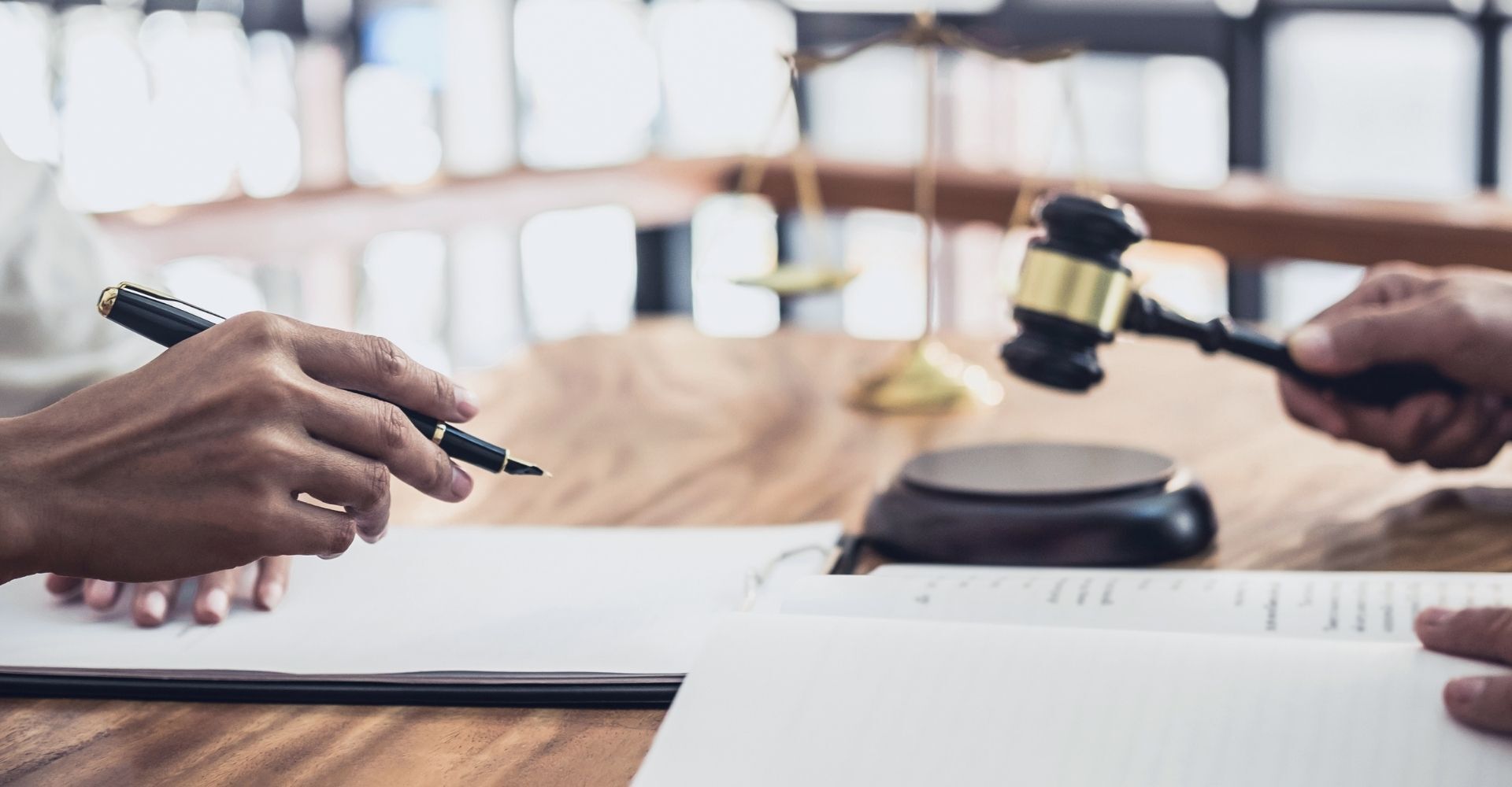 A judge is holding a gavel in front of a person sitting at a table.