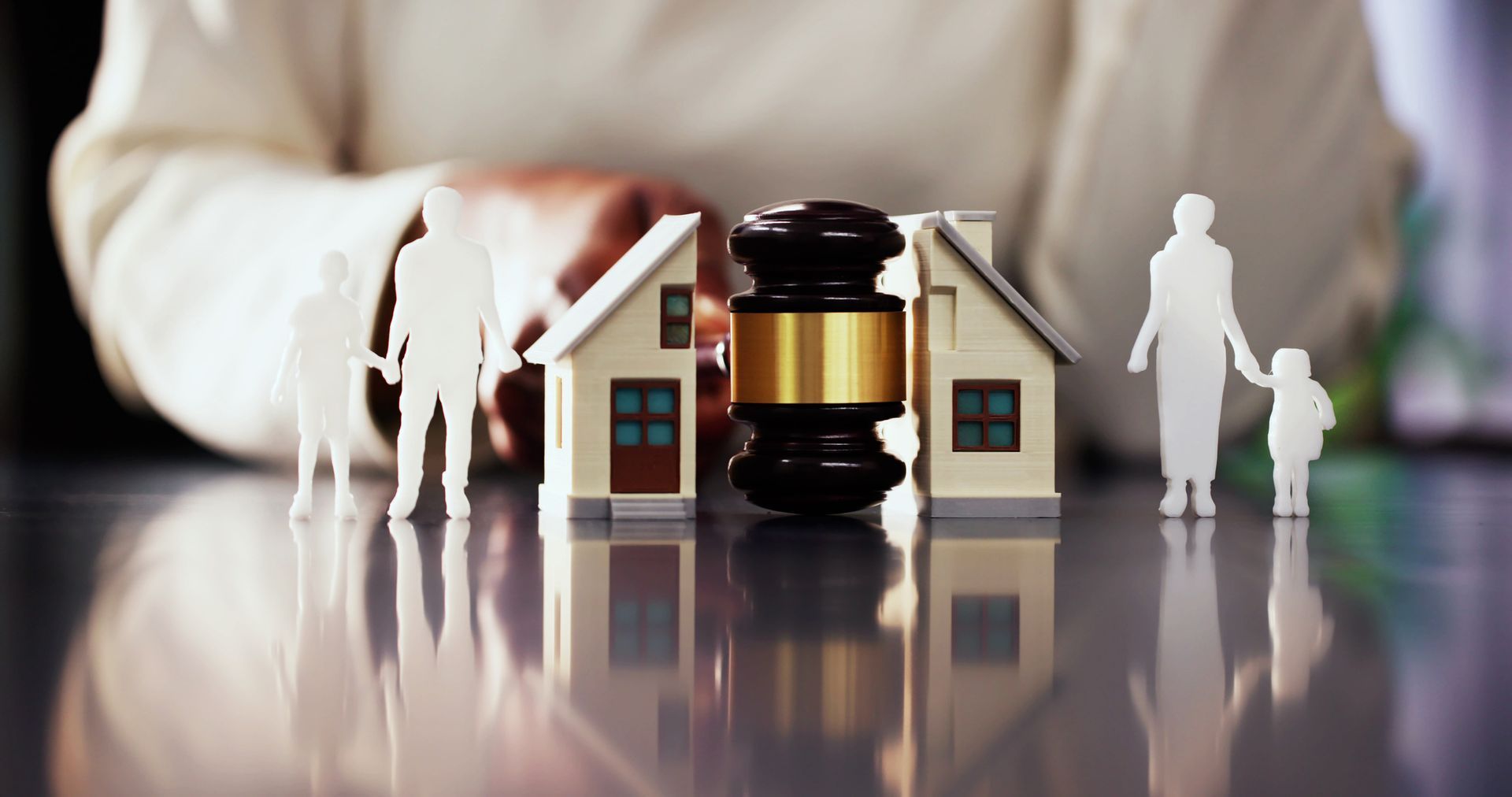 Toy houses and figures flank a judge’s gavel, symbolizing a property or legal dispute.