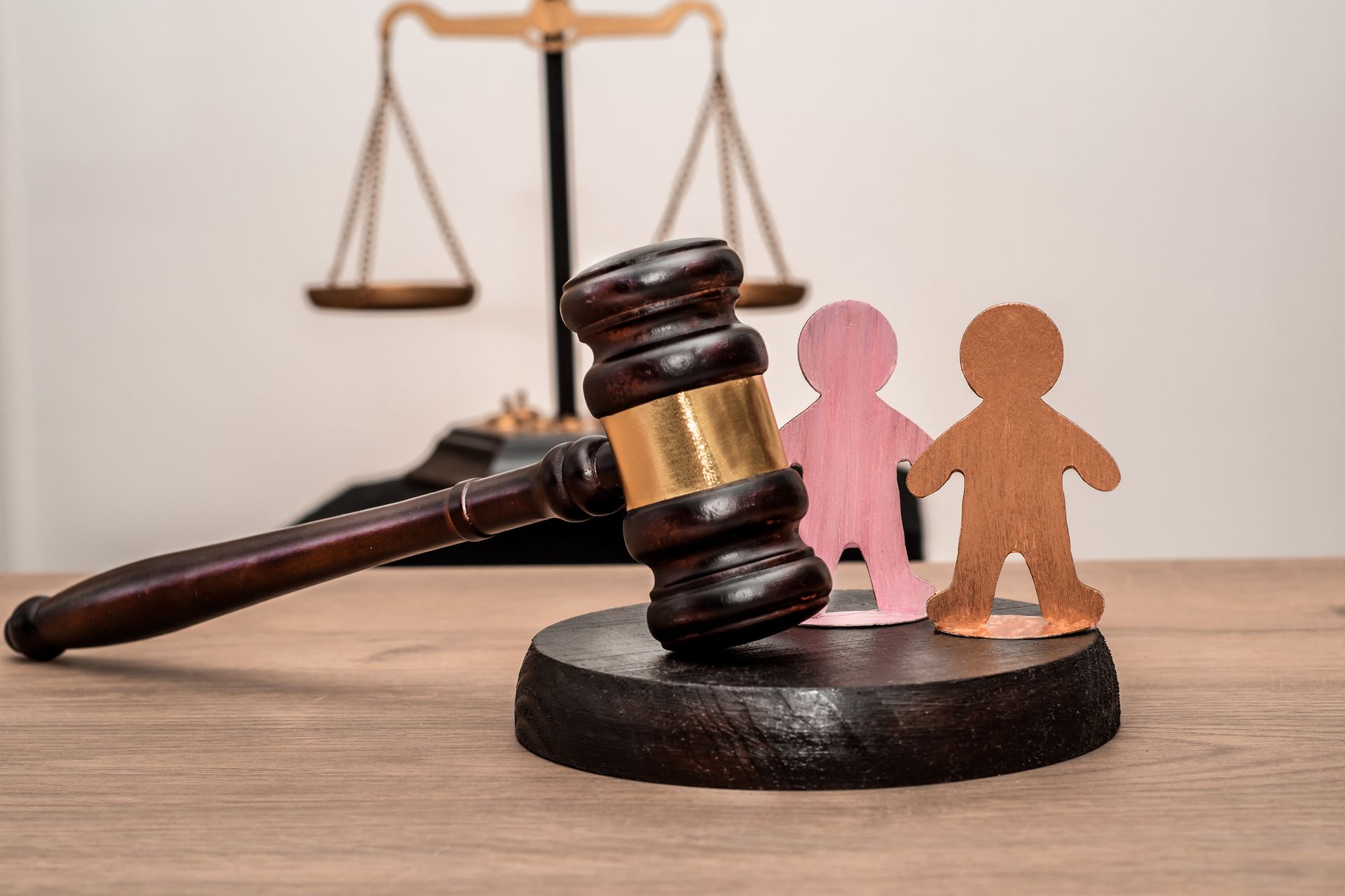 a gavel and wood cutouts of two children, with scales of justice in the background