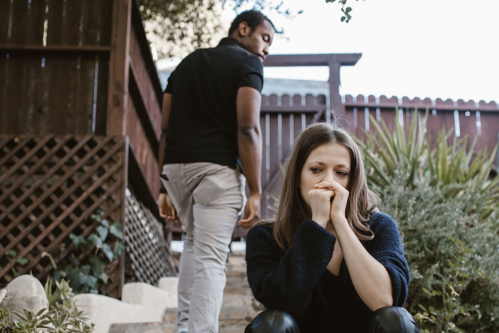 a woman crying and wearing black, while a man walks away