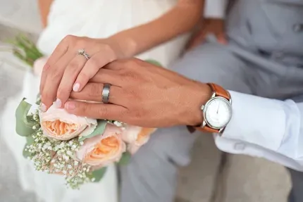a bride and groom with their hands on a wedding bouqet